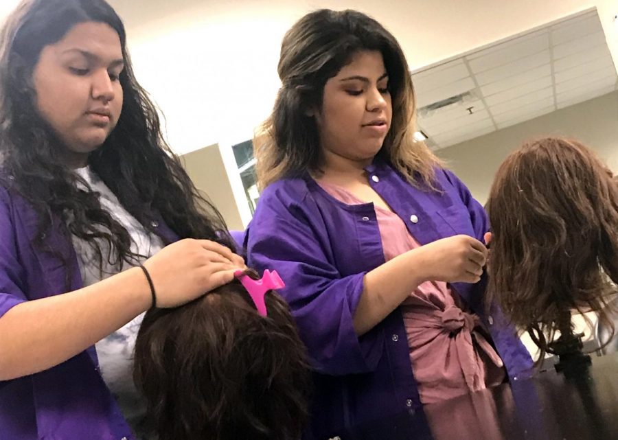 Seniors Evelyn Barcenas, left, and Rosalina Cruz Ortiz practice their cosmetology skills on dummy heads. Clients pay for services, but mainly to cover the cost of materials. 