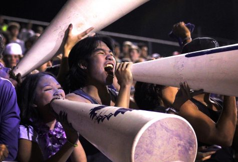 McKenzie Le, left, and Anthony Ly yell chants through cheerleader megaphones from the student section during the annual Mid-County Madness rivalry football game with Nederland on Friday, Sept. 24 at Indian Stadium (Kindred Nguyen/NDN Press)