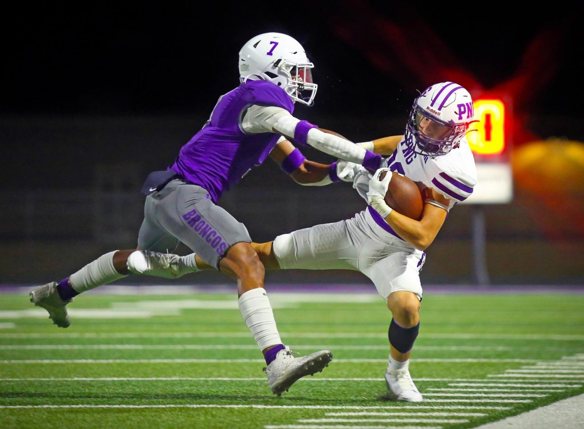 Struggling to stay upright, varsity football player Tyce Benkert (‘26) falters near the sideline during the regular-season finale at Dayton on Friday, Nov. 8, 2024. 

With PNG up 7-0, the Indians faced a 3rd-and-9 with just over six minutes left in the first quarter. 

As the defense rushed in, quarterback Connor Bailey (‘26) remained steady and hit Benkert as he crossed the middle of the field where he took the ball toward the sideline for an 18-yard gain to keep the drive alive. 

Plays later, running back Tyson Henry (‘27) barreled through the Broncos’ defense for a 33-yard touchdown, helping to increase a lead the Indians would never be in danger of losing. 

The Indians would overpower Dayton, 30-3, helping to put the team in place to finish as district champs when Nederland eventually fell to Montgomery in overtime later that night. (Jozlyn Oglesbee/NDN Press)