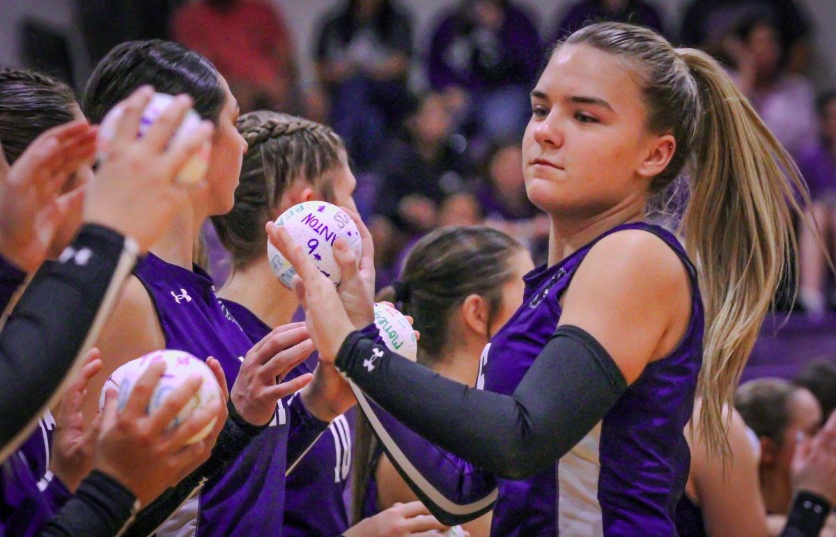 Varsity volleyball player Lillie Blanton ('26) claps hands with her teammates as she makes her way down a row of them during introductions before the home match with Nederland on Friday, Oct. 11, 2024. PNG lost the match, 0-3. (Arden Vandehoef/NDN Press)